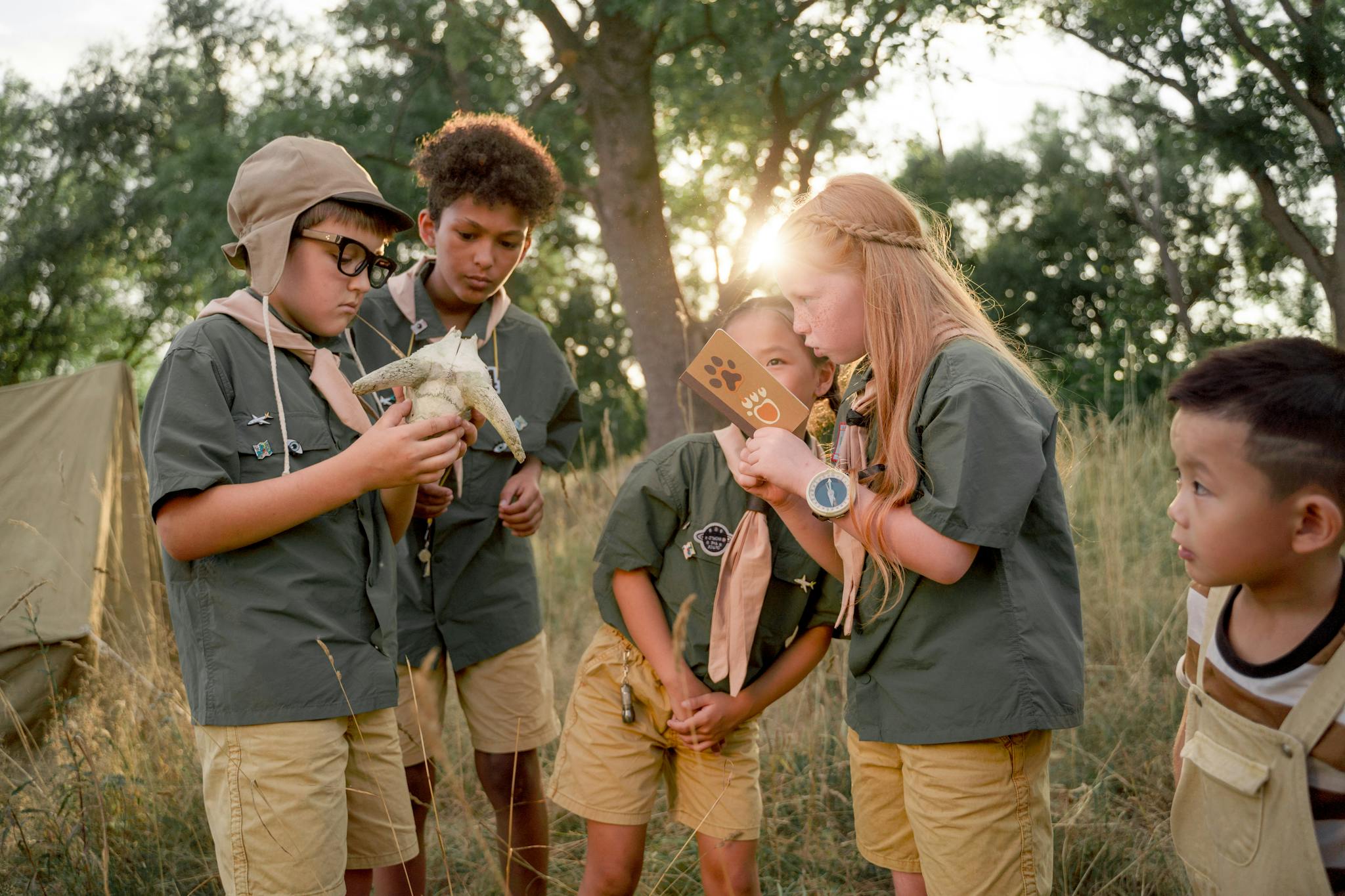 Group of children examining nature during summer camp, enjoying outdoor adventure.
